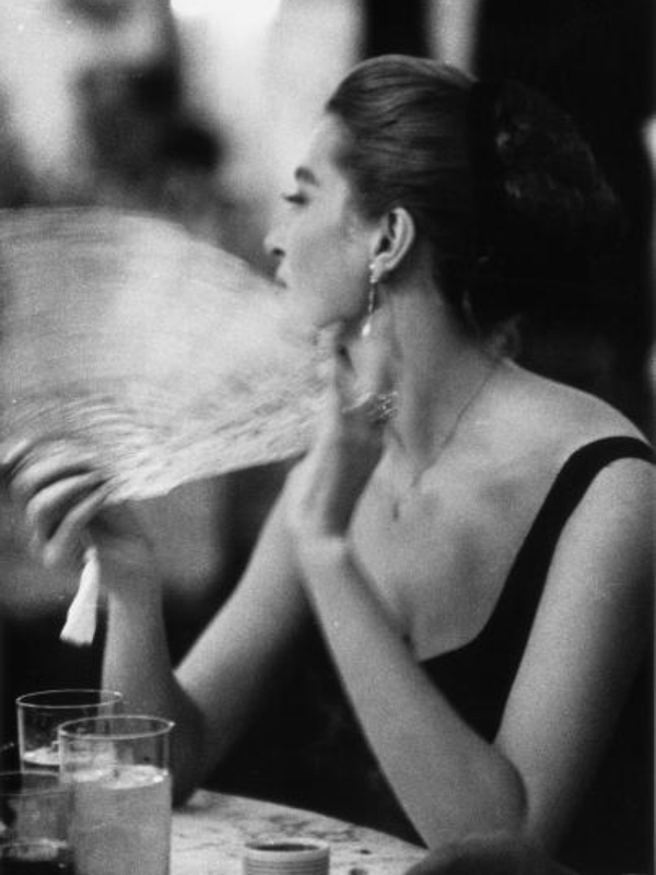 woman fanning herself at the horse races