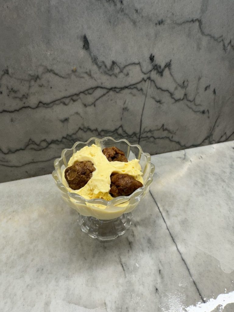 Vanilla ice cream topped with cookie dough in glass bowl