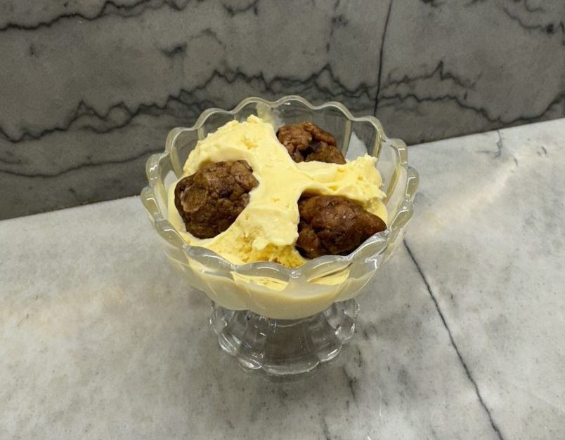 Vanilla ice cream topped with cookie dough in glass bowl