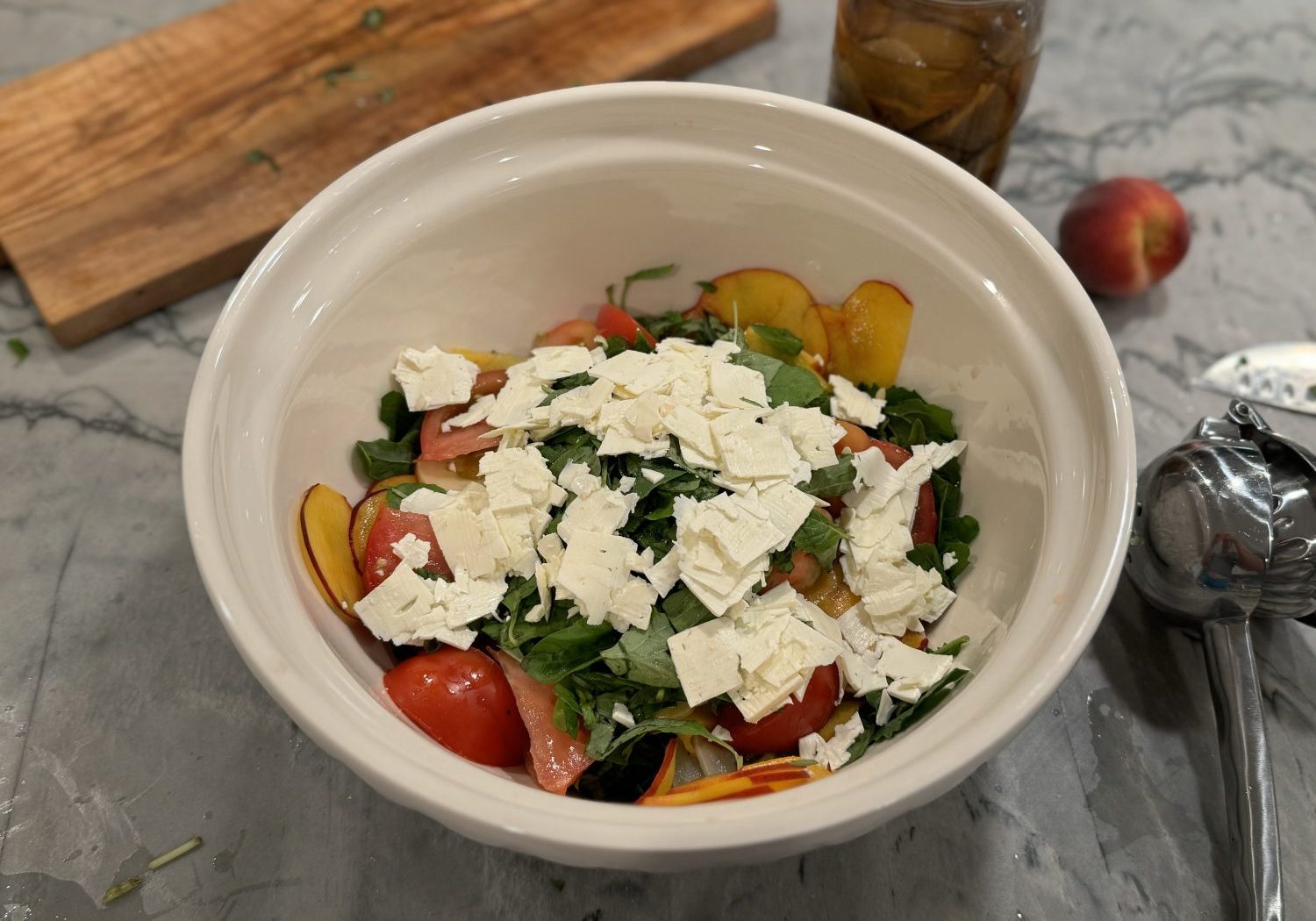 peach and arugula salad in big white salad bowl