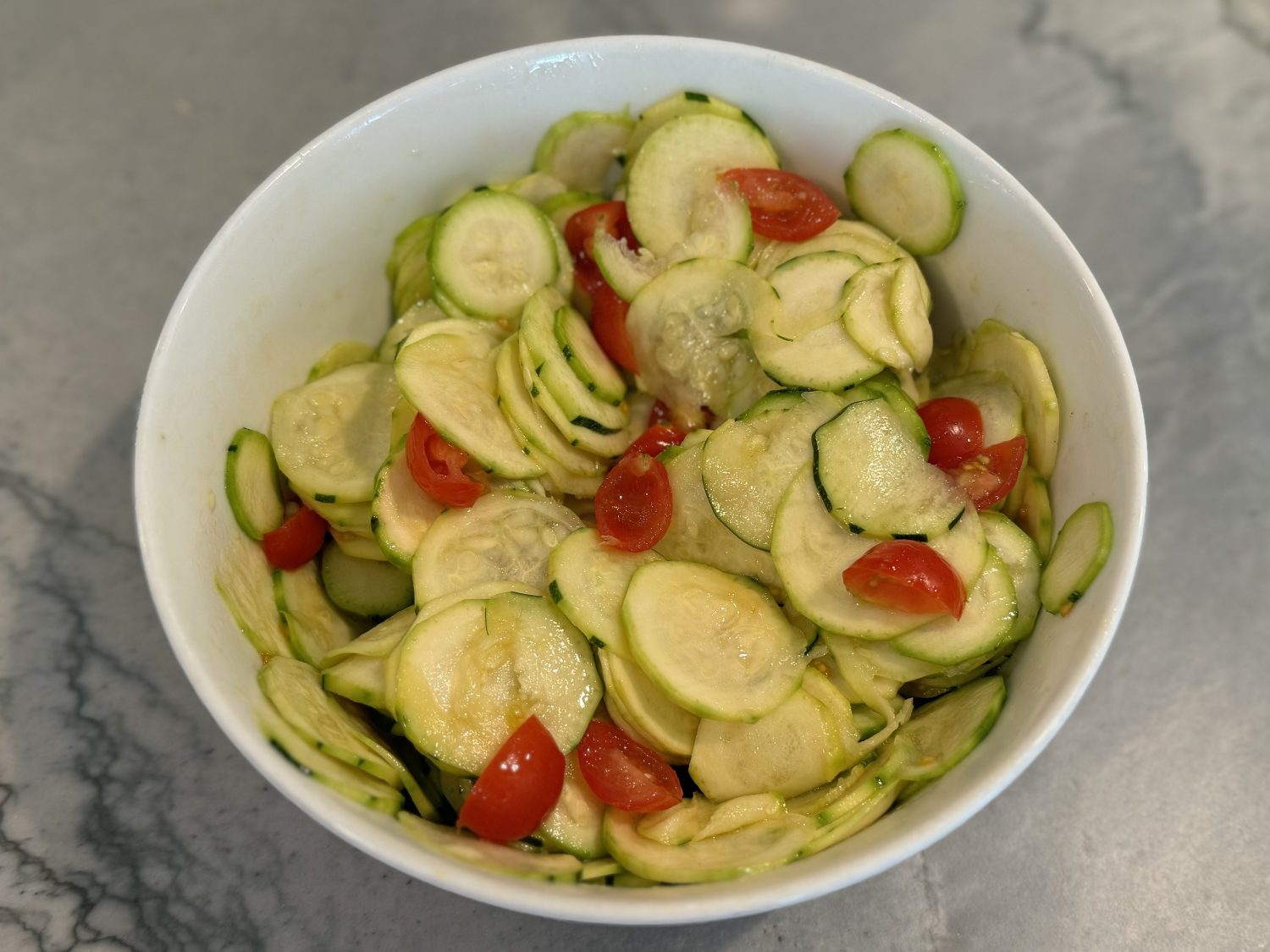 shaved zucchini salad with tomatoes in white bowl